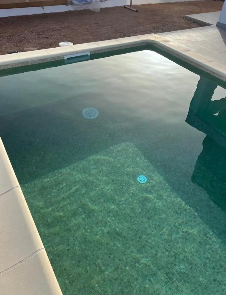 Piscina con revestimiento verde oscuro y efecto espejo en el agua