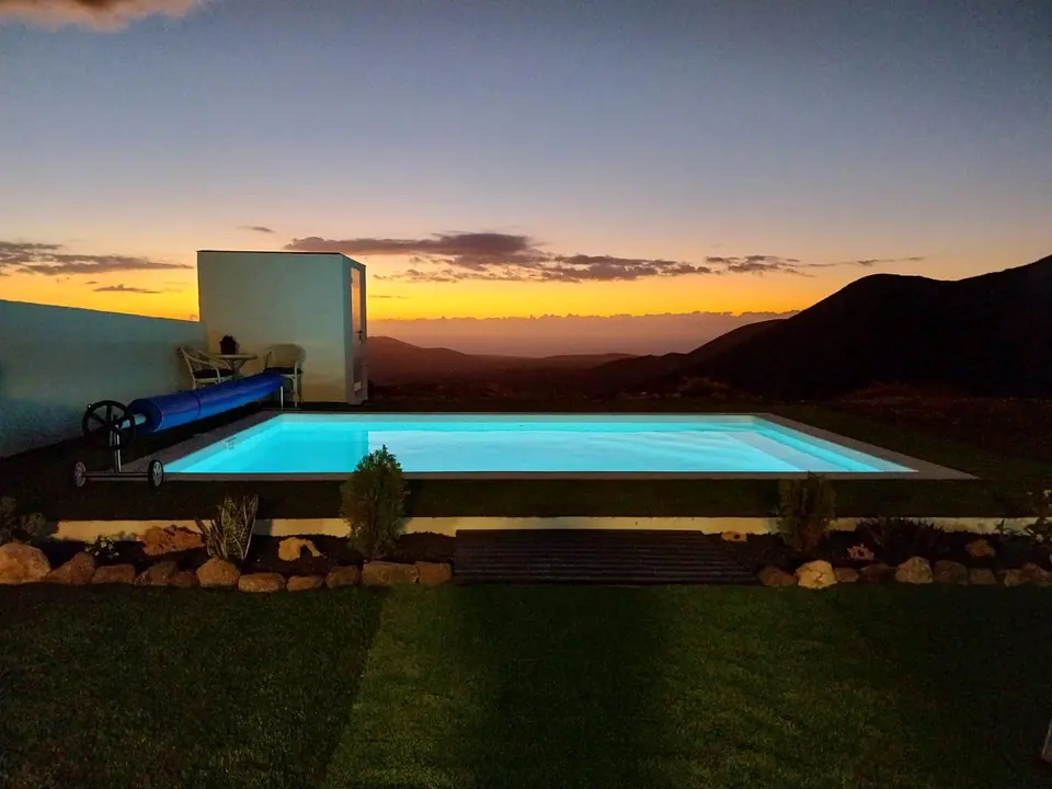 Piscina desbordante al atardecer con vistas a las montañas de Fuerteventura