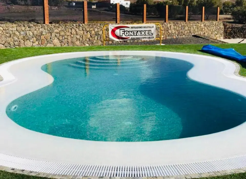 Piscina de forma libre en ocho con coronación blanca