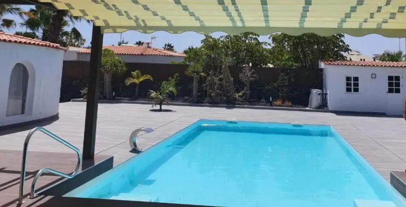 Piscina con cascada de acero inoxidable y jardín tropical