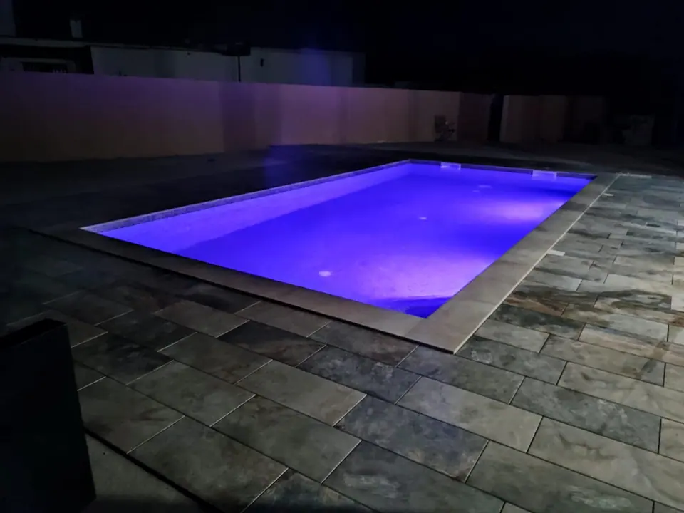 Piscina con iluminación LED violeta nocturna y suelo de pizarra