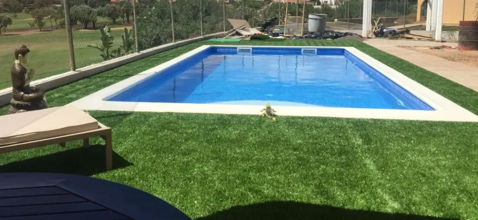 Piscina rectangular azul rodeada de césped