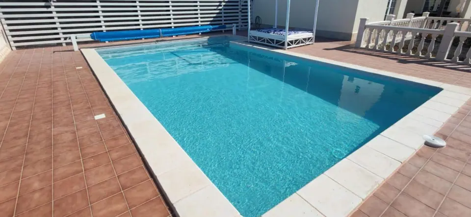 Piscina rectangular con coronación cerámica y playa de terracota