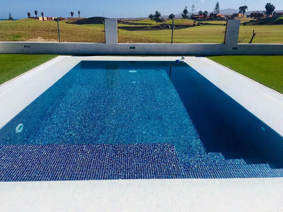 Piscina de gresite azul oscuro con escalera interior de obra
