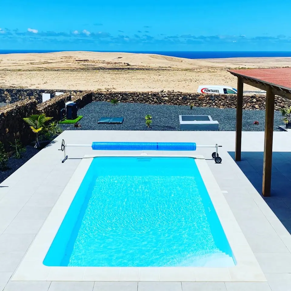Piscina con cobertor enrollable y muro de piedra volcánica