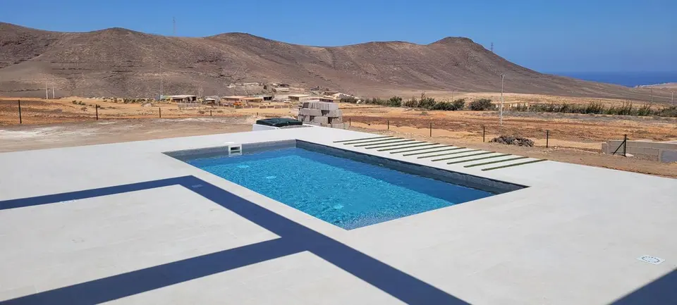Piscina con franjas decorativas en el solado y montañas de Fuerteventura
