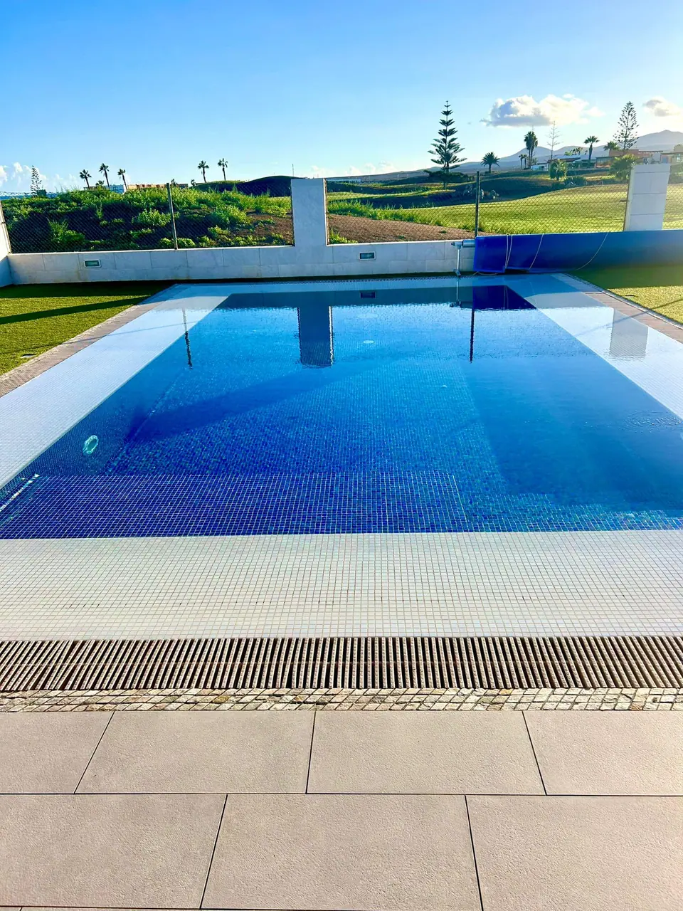 Piscina de gresite azul con rebosadero perimetral